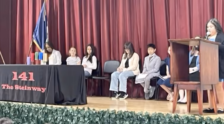 Students seated on stage during a PS 141 Steinway school ceremony