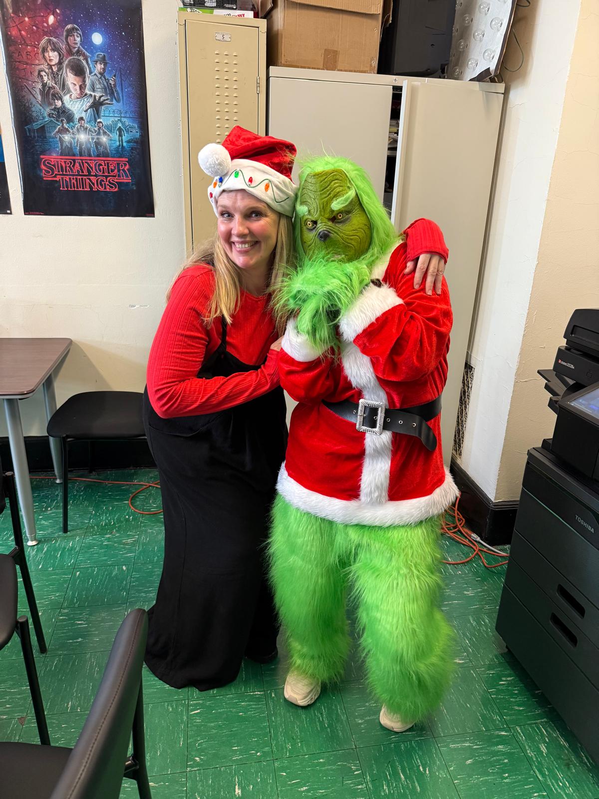 Staff member posing with Grinch costume character during holiday event