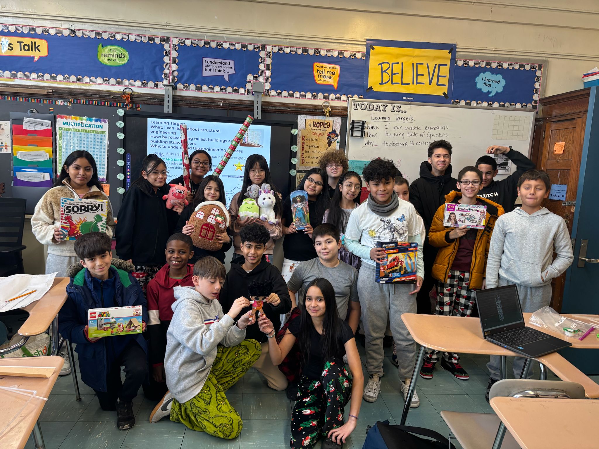 Students displaying donated toys and games in classroom holiday drive