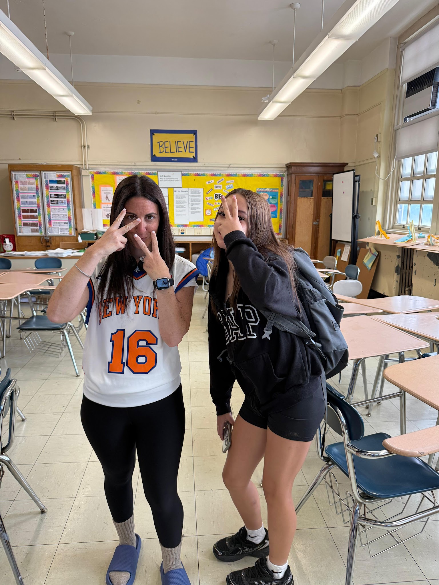 Teacher and student posing playfully together in classroom