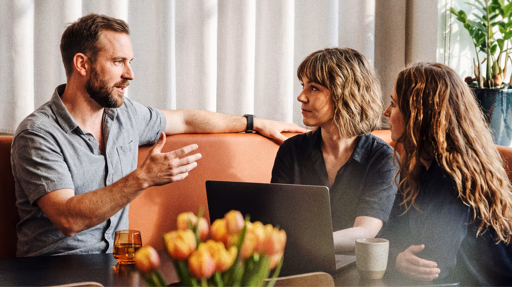 A consultant talking with two colleagues over a laptop