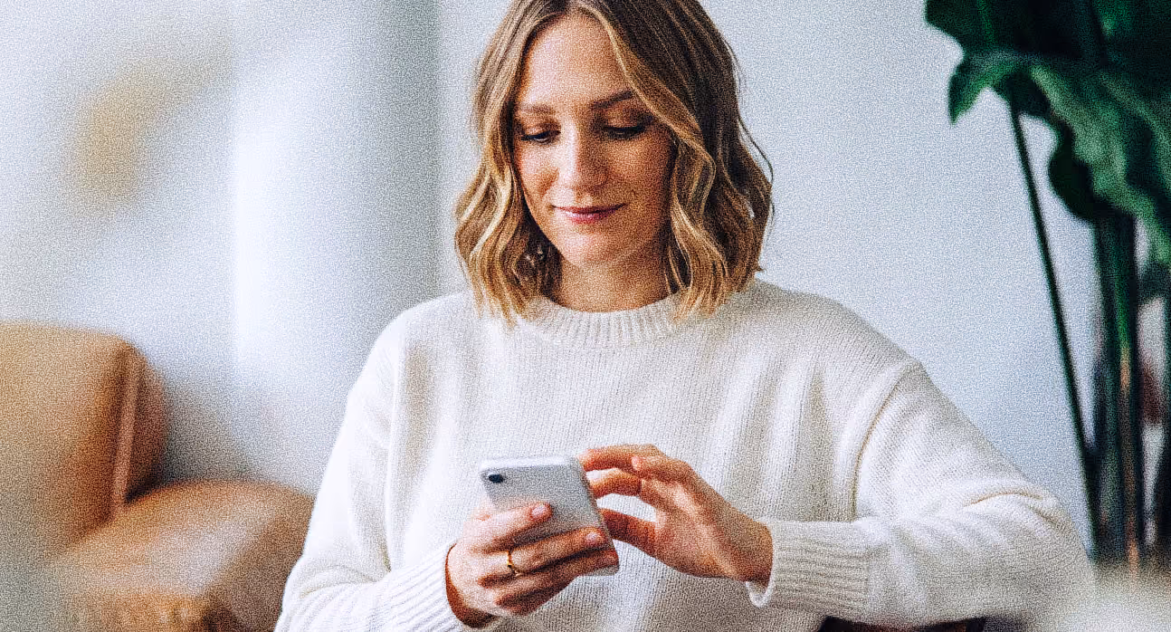 A woman smiling while reading on her phone