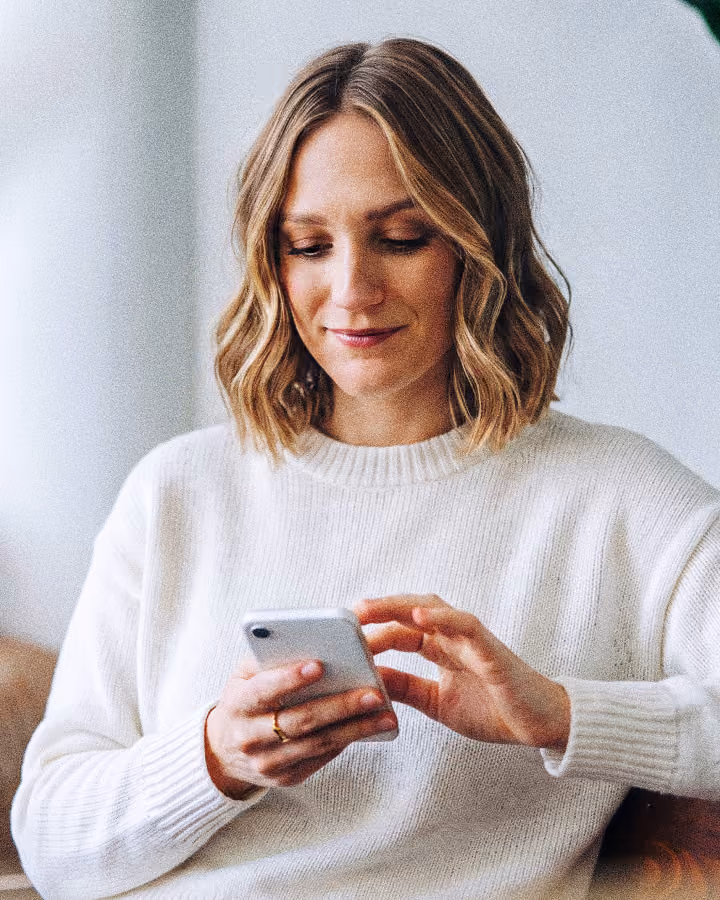 A woman smiling at her phone at work