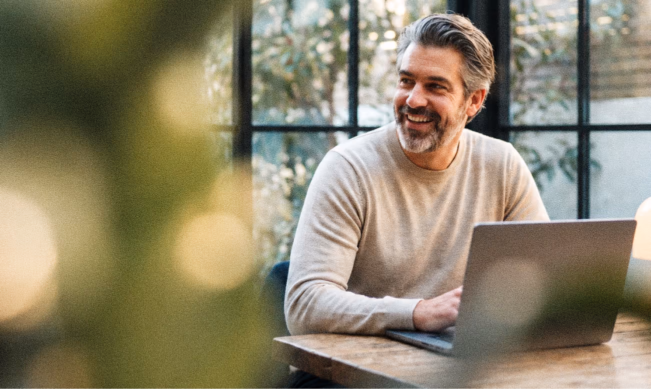 A man smiling while working on his laptop