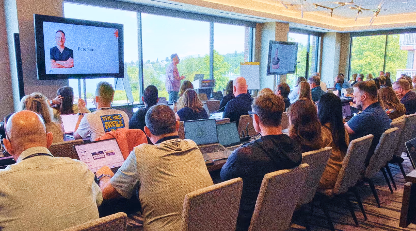 An AI training workshop with attendees working on laptops in a conference room