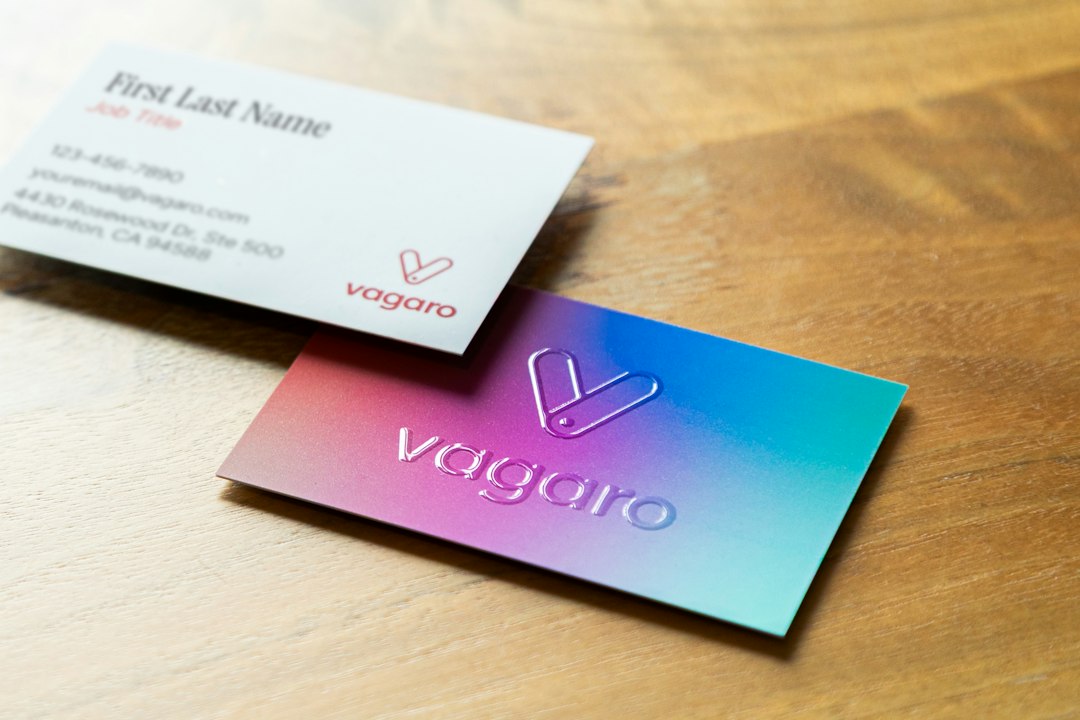 Two branded business cards laid on a wooden surface, showing consistent brand identity