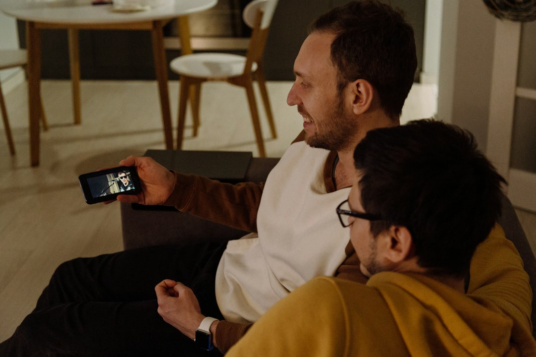 Two people sitting and watching a video together on a smartphone