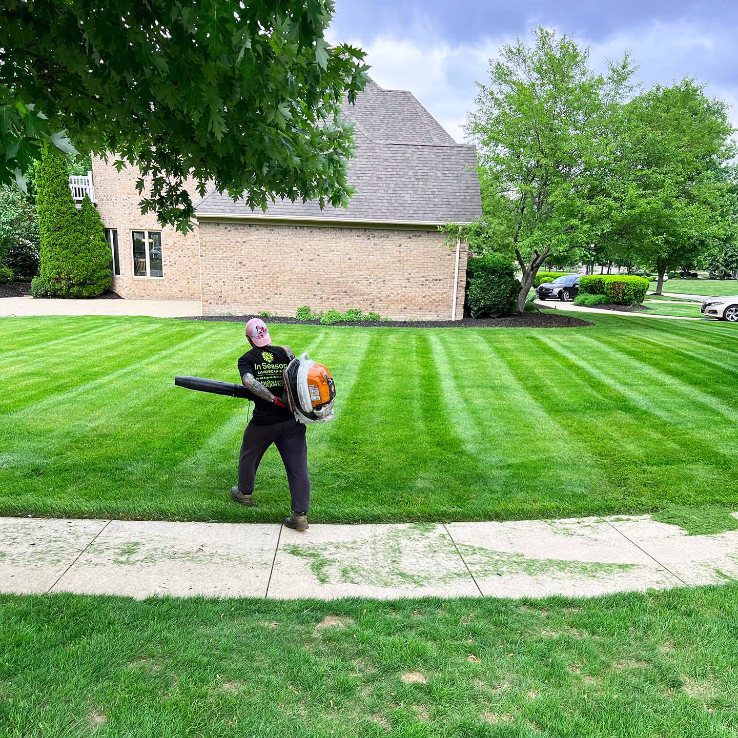 A worker blowing grass trimmers after a freshly cut grass in season landscaping
