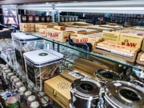 Shelf displaying RAW rolling papers, accessories, and containers in a vape or smoke shop.