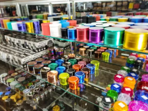 Colorful metal containers and accessories displayed on glass shelves in a store.