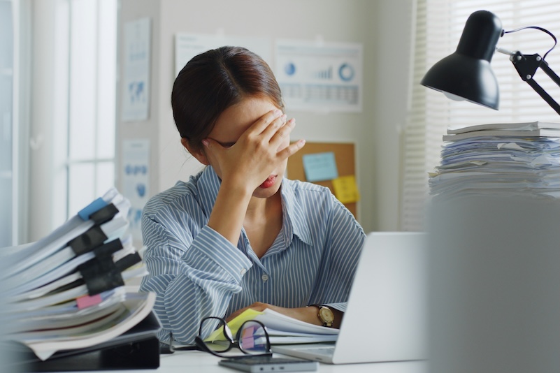 Image of an overwhelmed woman surrounded by paperwork