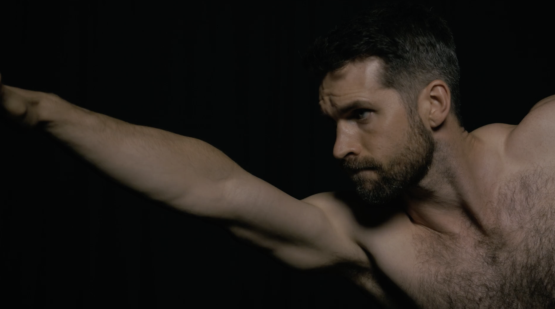 Dean Pohlman in profile, lit against black, from the Man Flow Yoga founder story