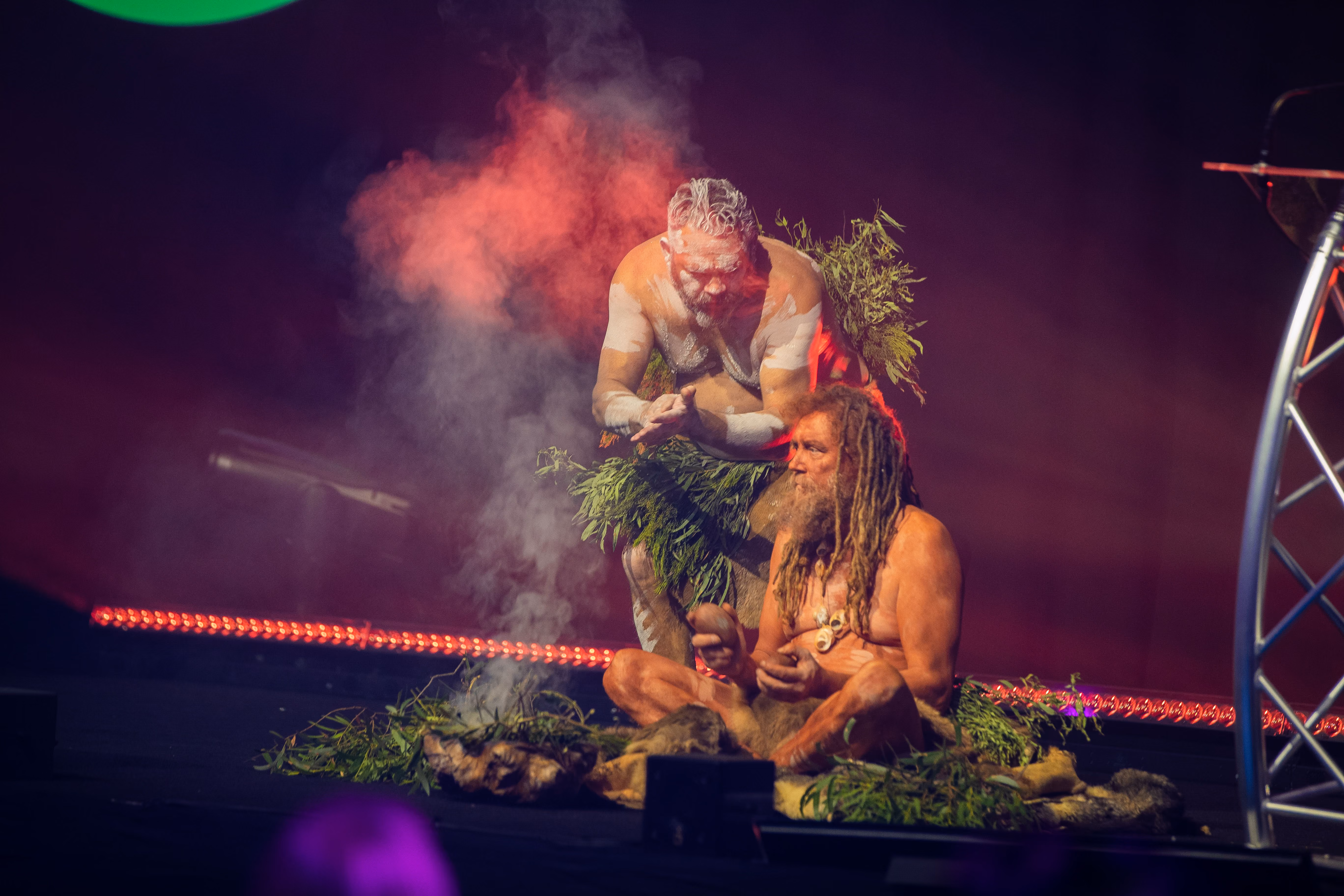 Two men performing a smoking ceremony on stage.