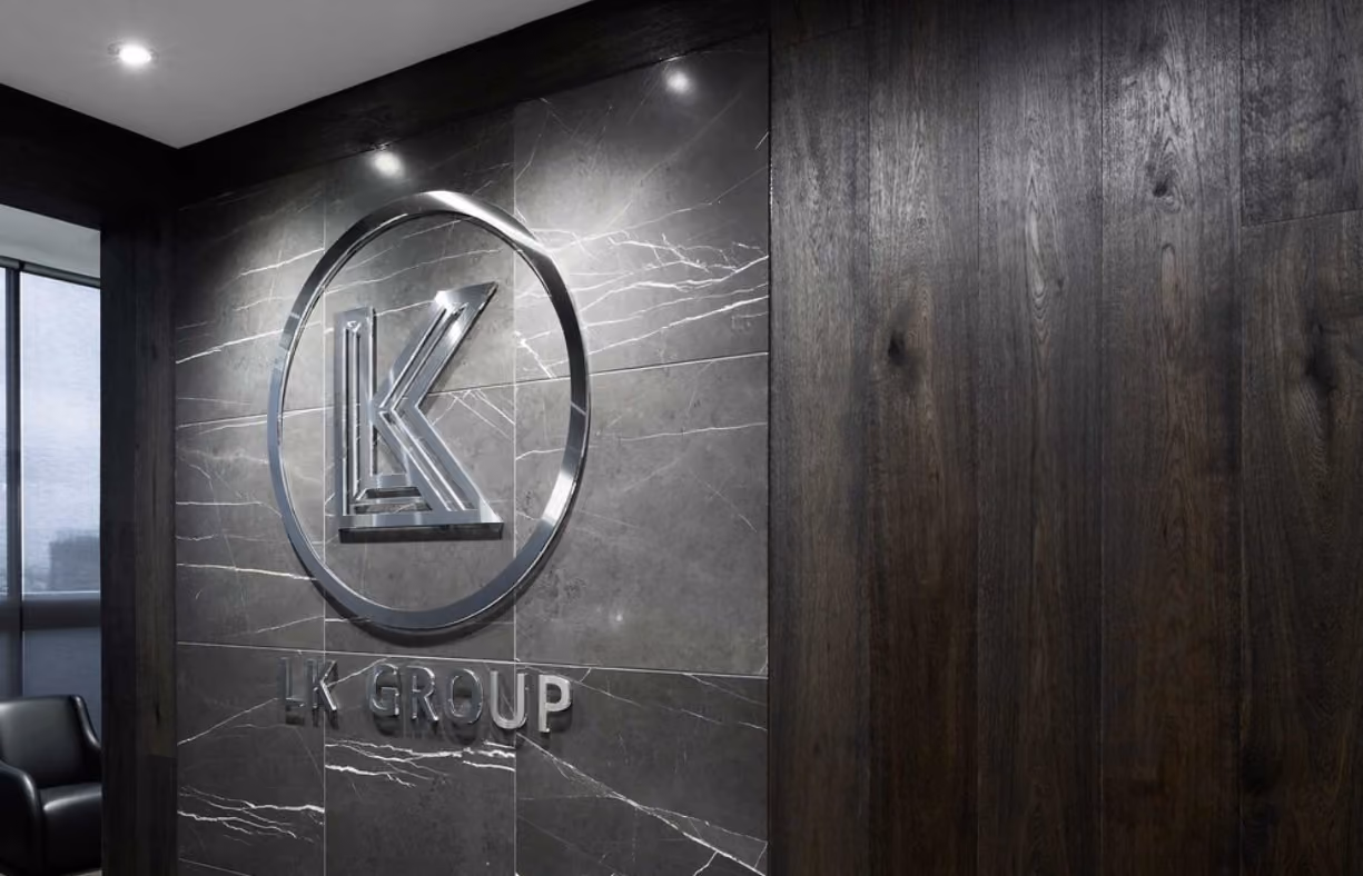 Metallic LK Group logo mounted on a dark marble wall in a modern office setting.