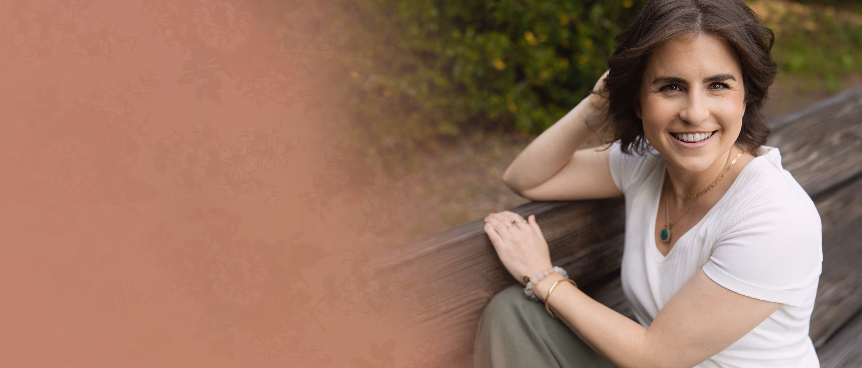 Leah Hoffman sitting on a wooden bench outdoors, wearing white top.