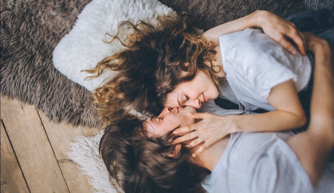 Couple lying close on rugs with foreheads touching and eyes closed in a tender moment.