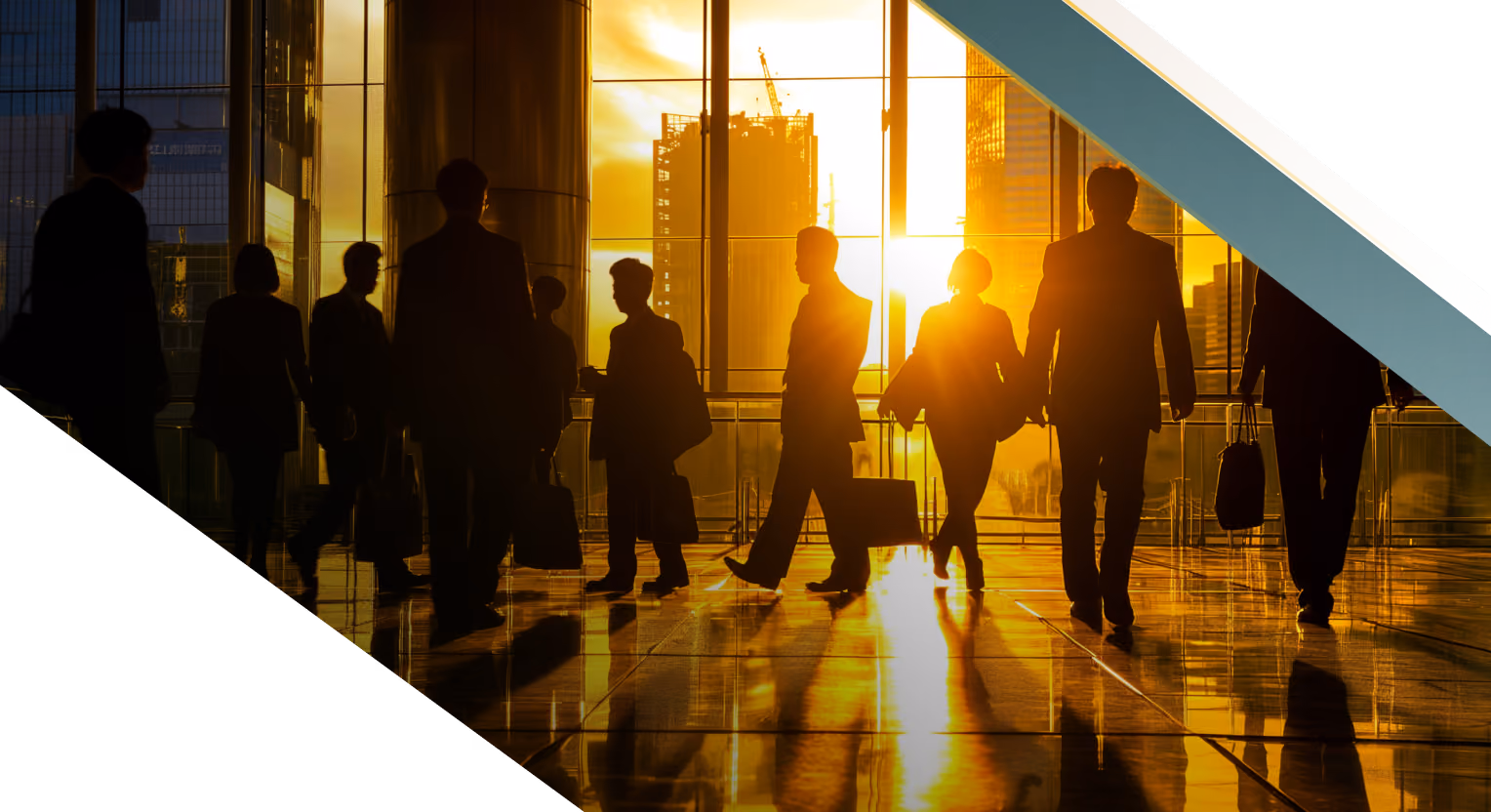 Silhouettes of people walking and carrying briefcases inside a modern building with large windows during sunset, with city buildings and construction cranes visible outside.