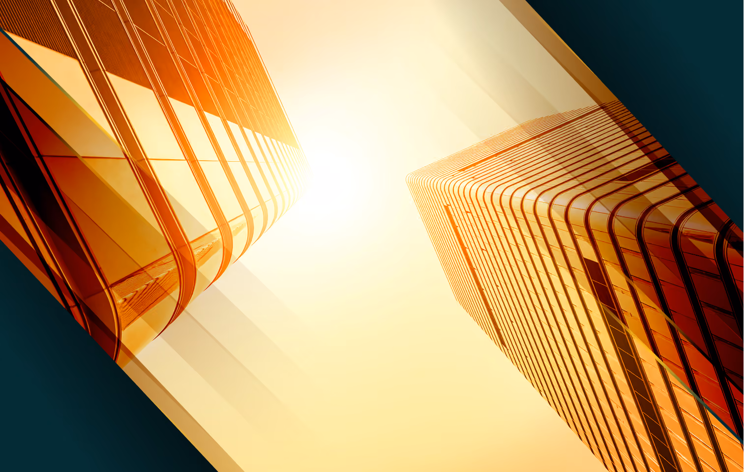 Low-angle view of two modern glass skyscrapers reflecting orange sunlight against a clear sky.