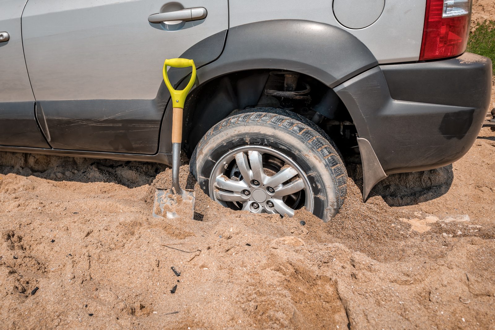 Vehicle stuck in sand with a shovel