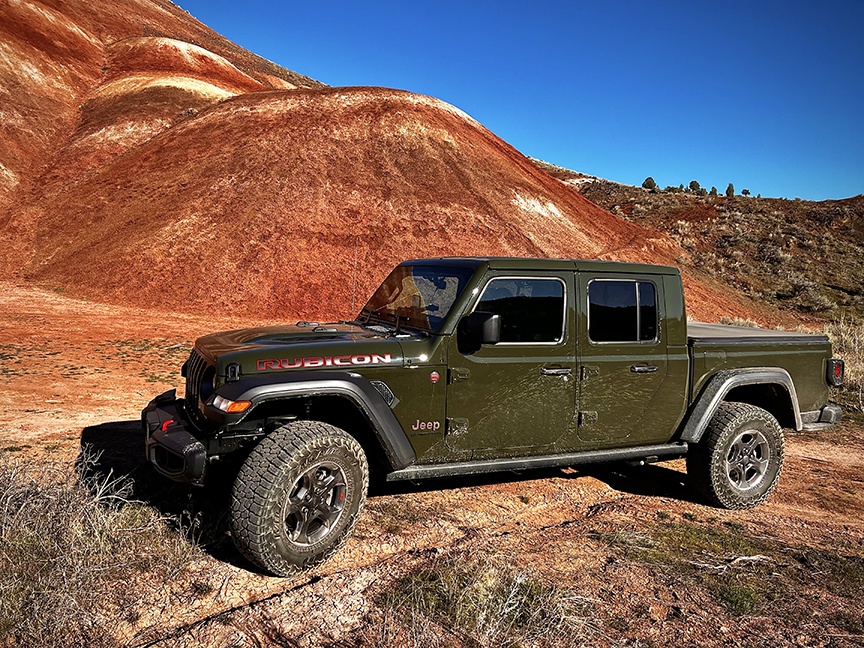 Green Jeep Gladiator below red and gold painted hills