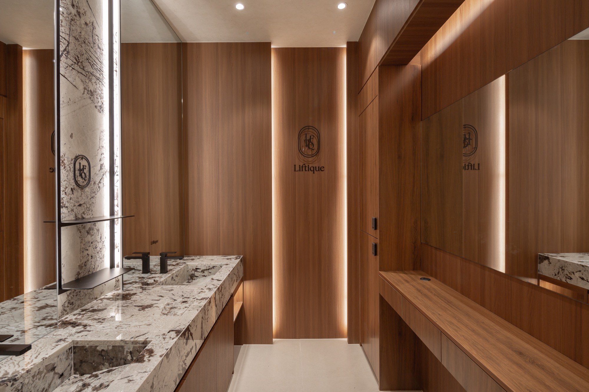 Powder room with wood cabinetry and stone sinks at Liftique Dermatology Clinic