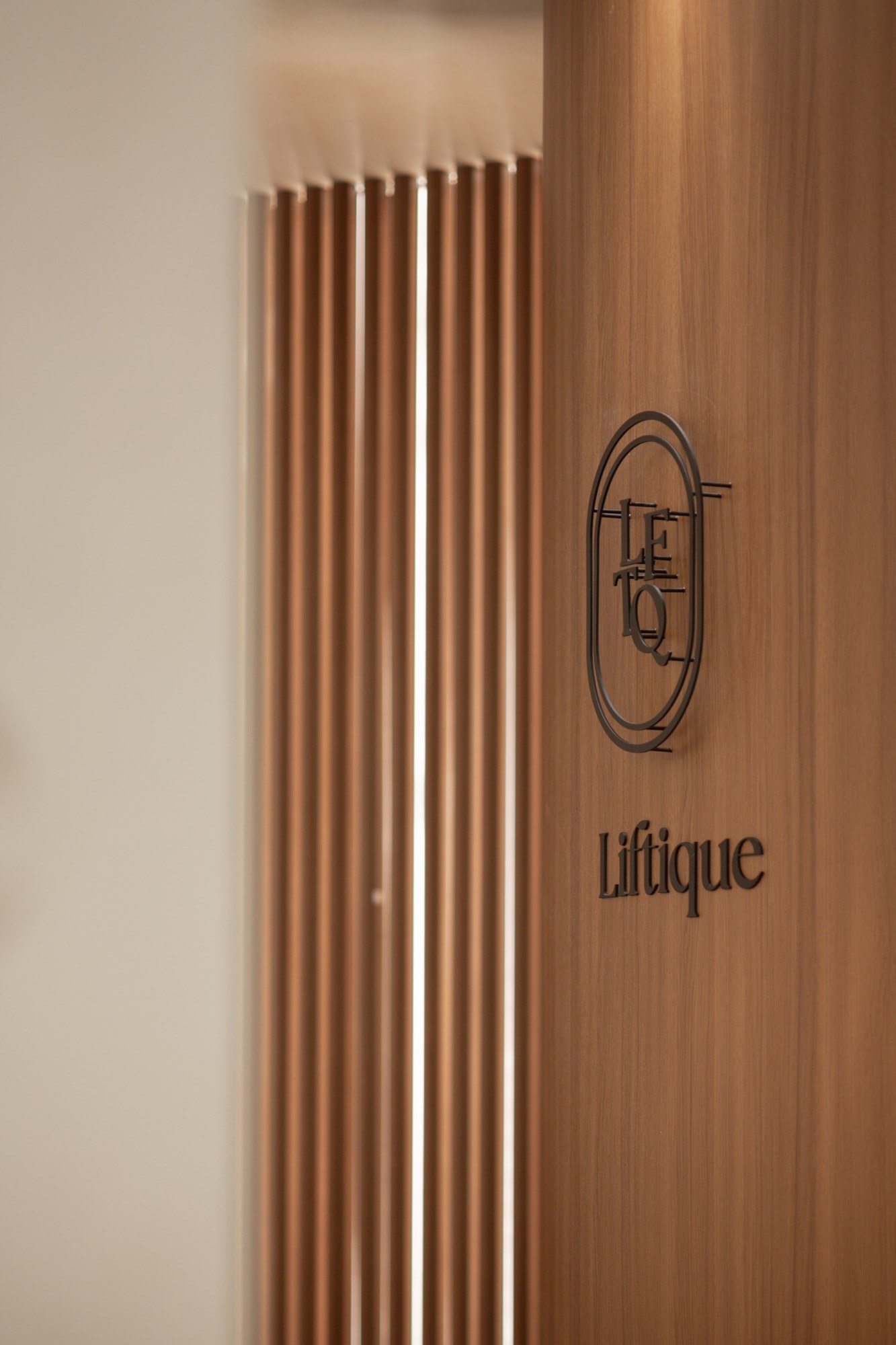 Liftique clinic logo mounted on a warm wood interior wall