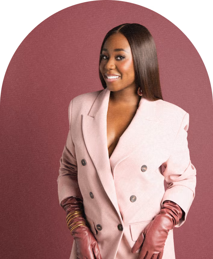 Smiling woman with long straight hair wearing a light pink double-breasted blazer and dark red leather gloves, posed against a solid dark pink background.