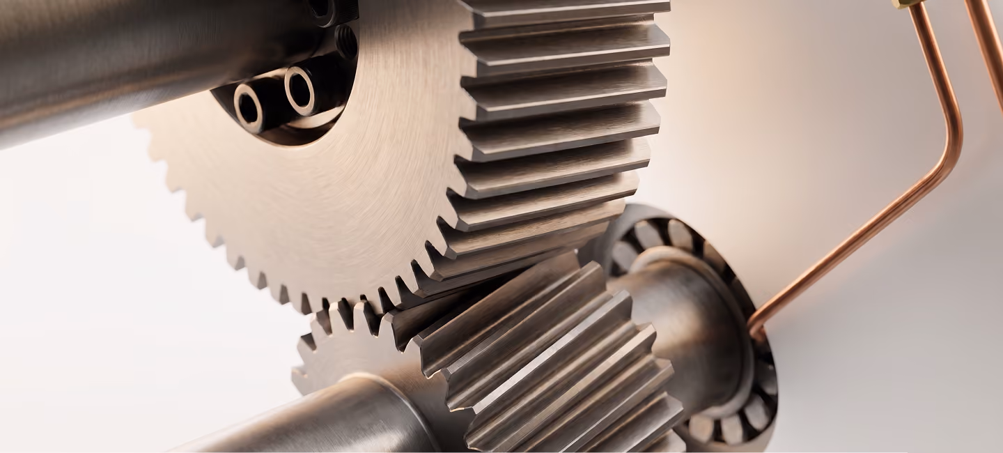 Close-up of two interlocking metal gears mounted on shafts, showing detailed teeth and smooth metallic surface with a connected copper tube.