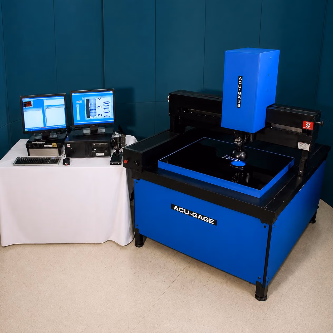 Blue and black ACU-GAGE precision measurement machine with a computer setup on a table beside it, displaying measurement data on two monitors.