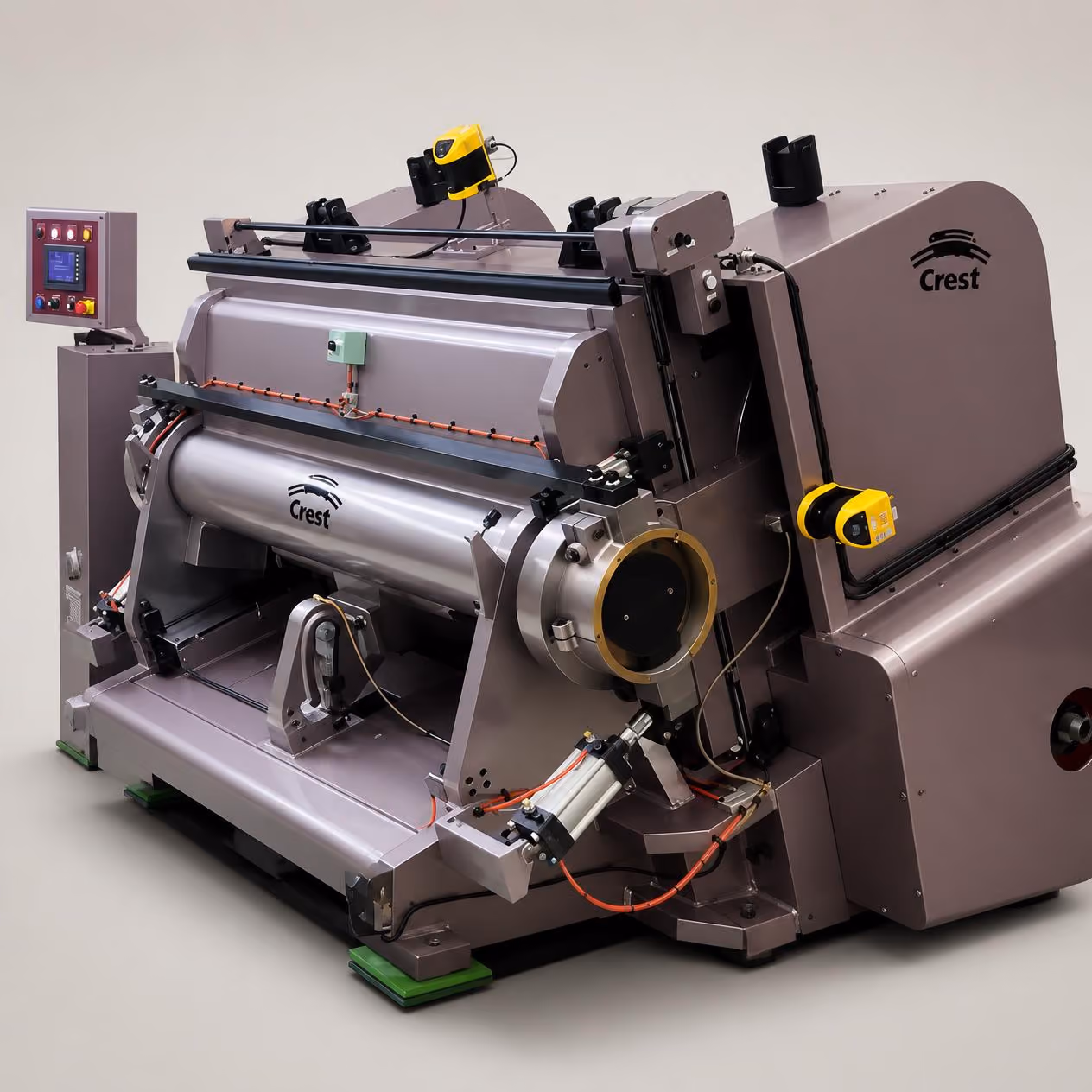 Large industrial machine with a cylindrical metal drum labeled Crest, multiple mechanical components, sensors, and control panel housed in a gray frame on green pads.