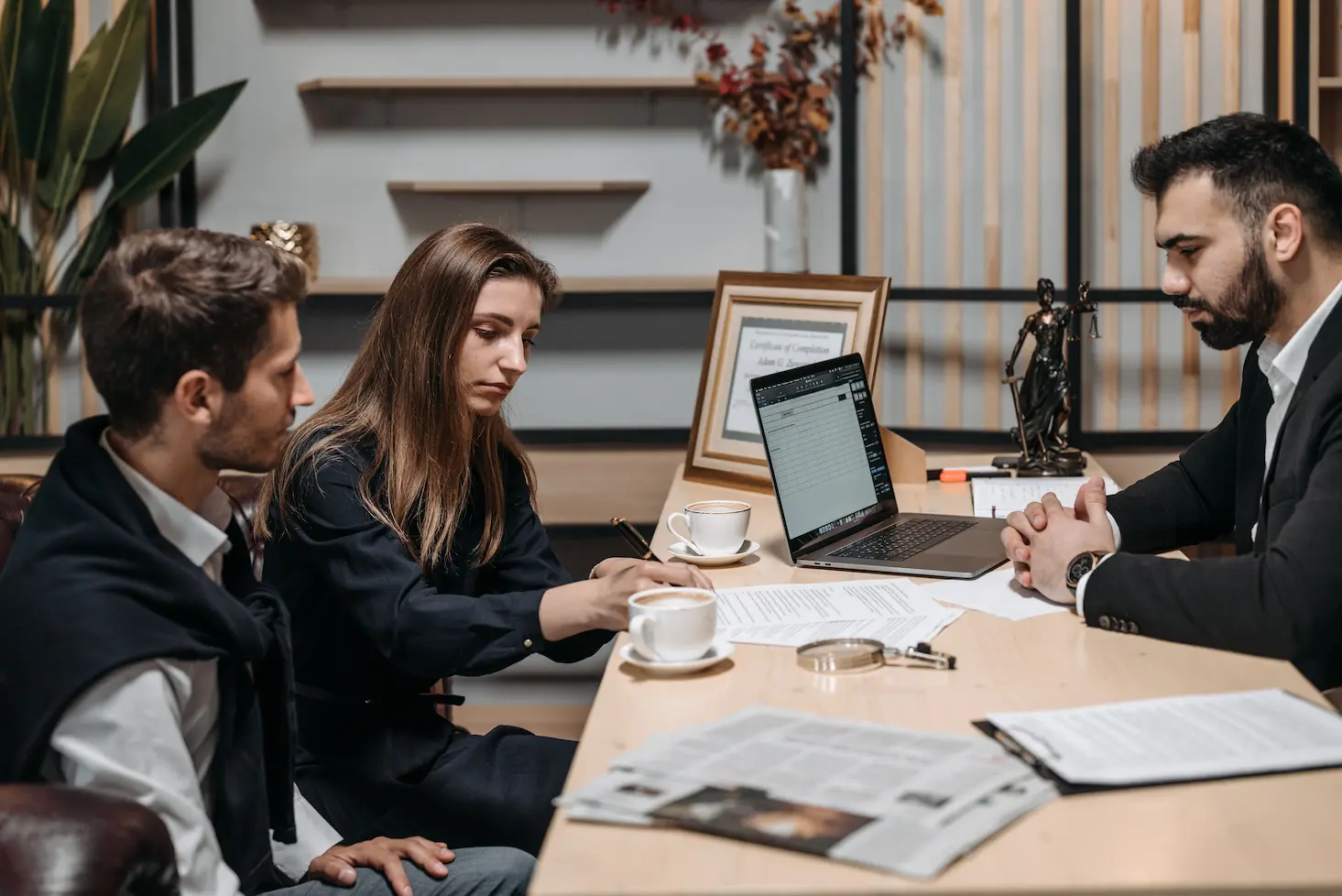 Trois professionnels discutant de documents autour d'un café dans un bureau