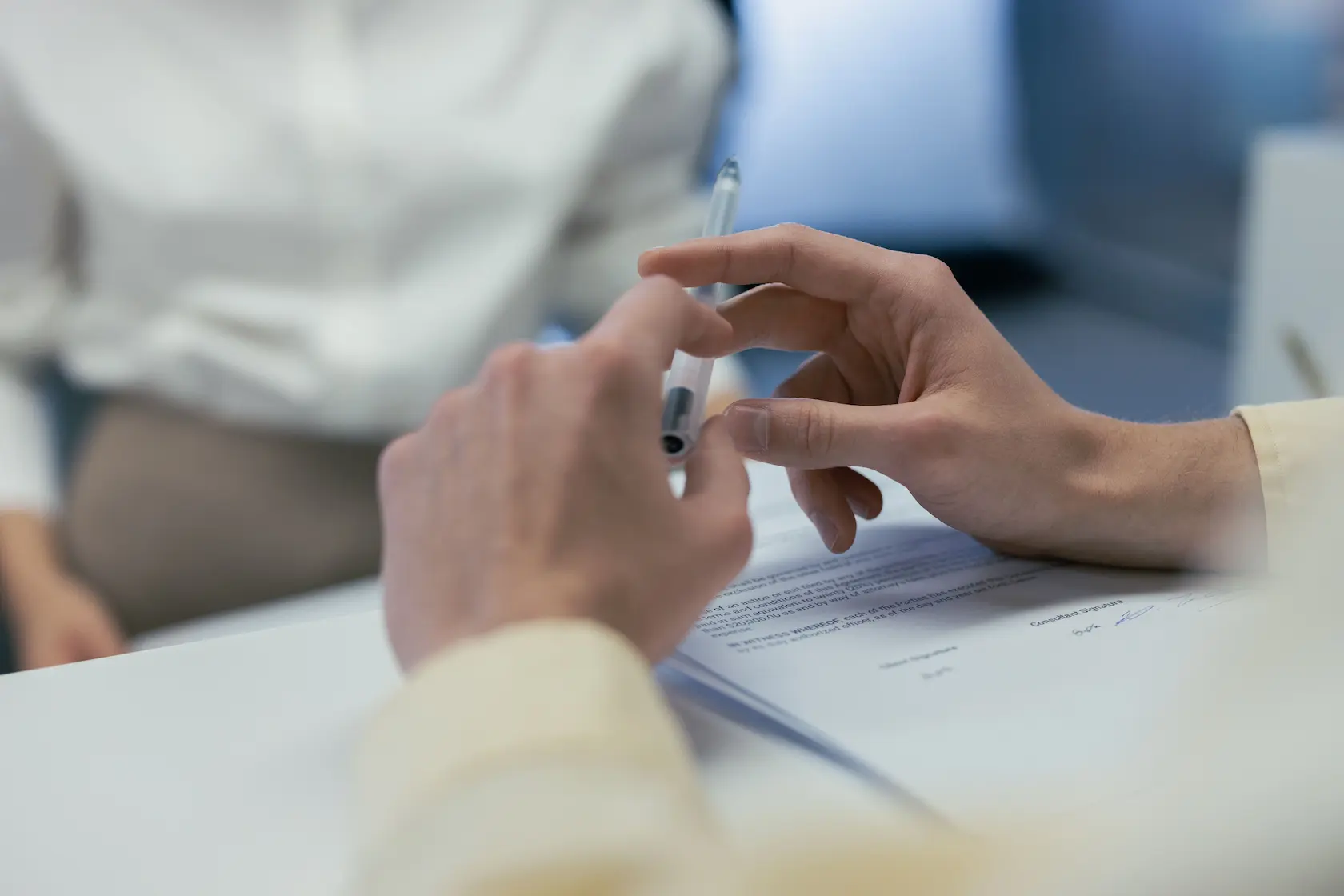 Gros plan sur des mains tenant un stylo lors d'une réunion d'affaires ou de la signature d'un contrat.