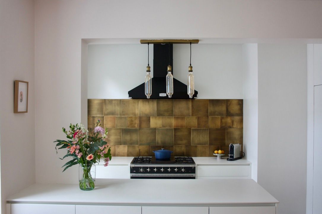 Keuken met messing spatwand en zwarte dampkap