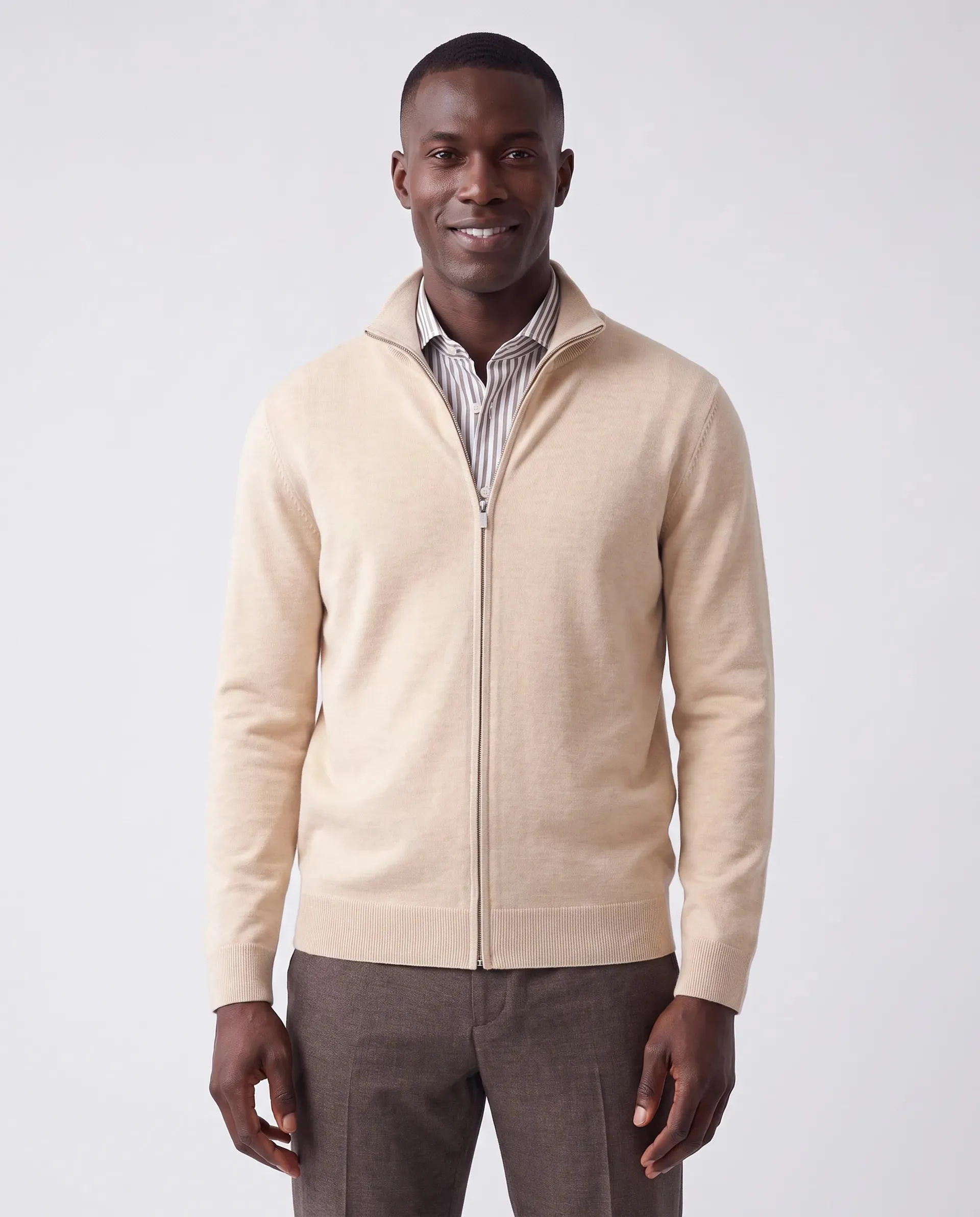 On-model productfoto: lachende man in een beige vest met rits over een gestreept overhemd en een bruine broek