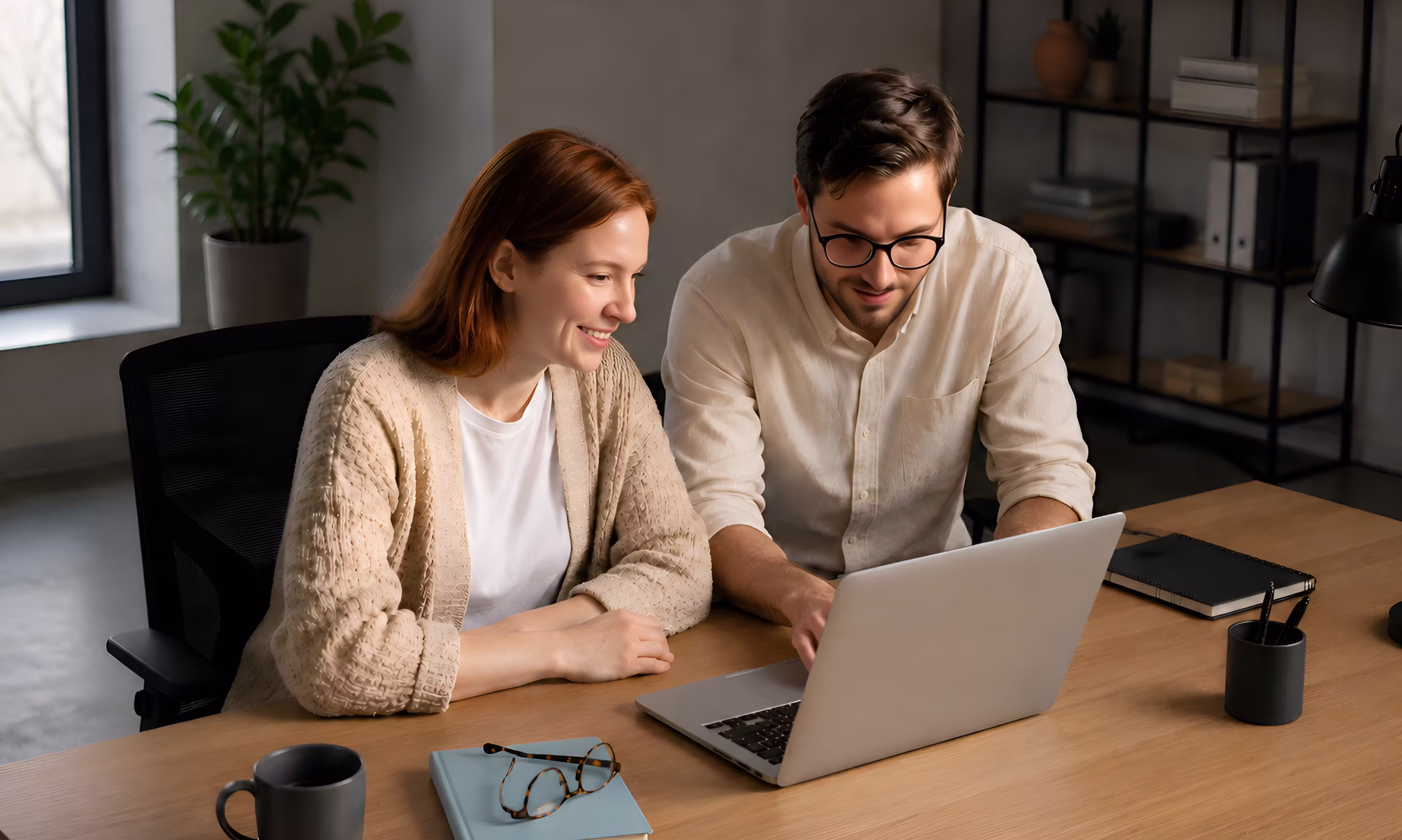 Two colleagues reviewing financial data together on a laptop at the office