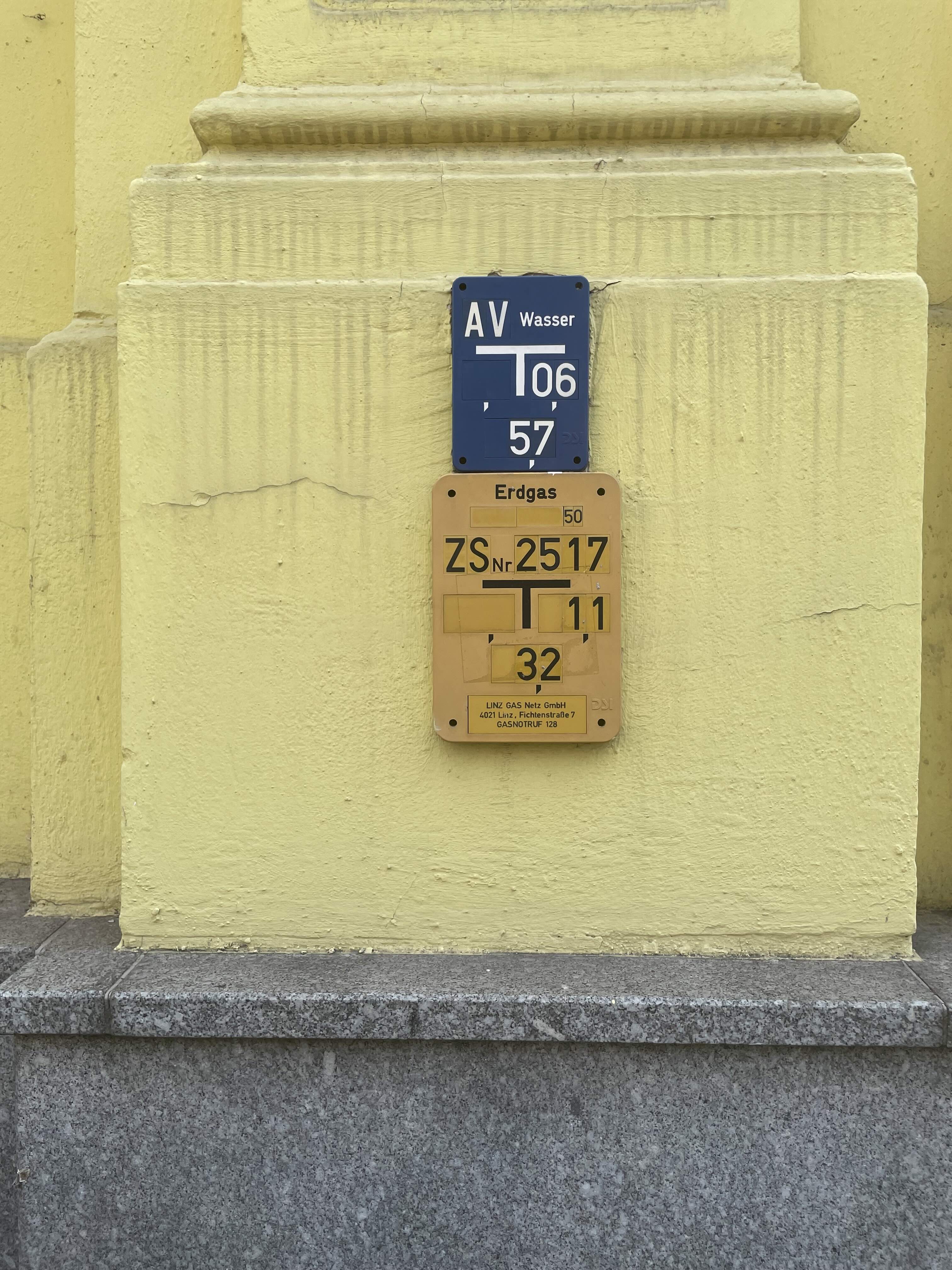 Close-up photograph of the yellow wall and gas infrastructure plate in Linz that inspired this article