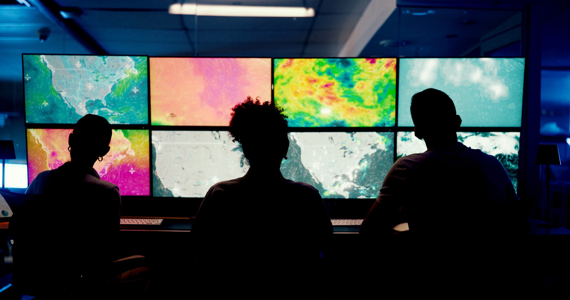 Operators in front of a wall of monitoring screens