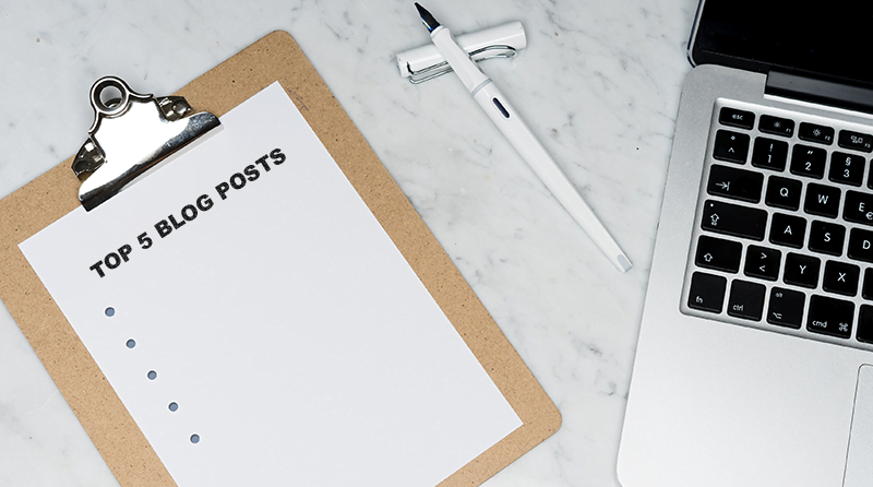 A clipboard with a piece of paper, pen and laptop computer on a table representing top posts and API security