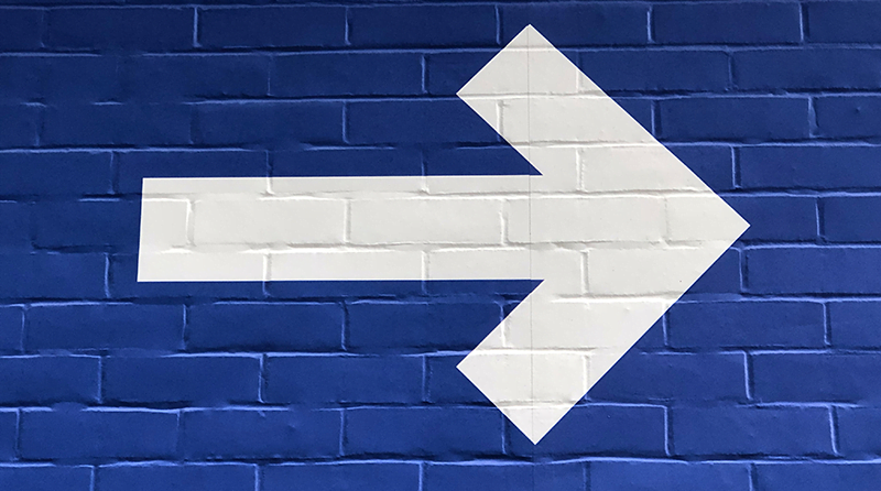 A blue brick wall with an white arrow on it pointing to the right representing account breach