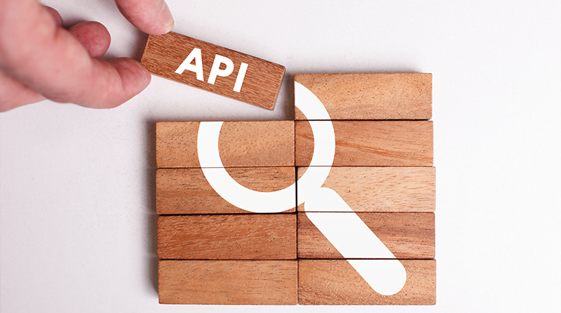 Wooden blocks stacked with a magnifying glass on them and a hand removing one block that has API printed on it representing excessive data exposure