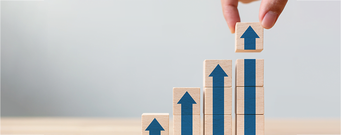 A person stacking blocks with arrows pointing up in a format that looks like a stock chart.
