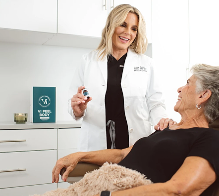 Smiling doctor in white coat holds bottle, talking to elderly woman reclining on exam chair.