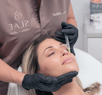 Woman receiving facial injection from gloved professional in a skincare clinic setting.