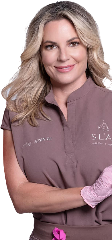 Woman with blond hair wearing mauve scrubs and pink gloves, smiling at the camera.
