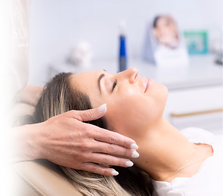 Woman receiving a gentle head massage while relaxing with eyes closed in a spa setting.