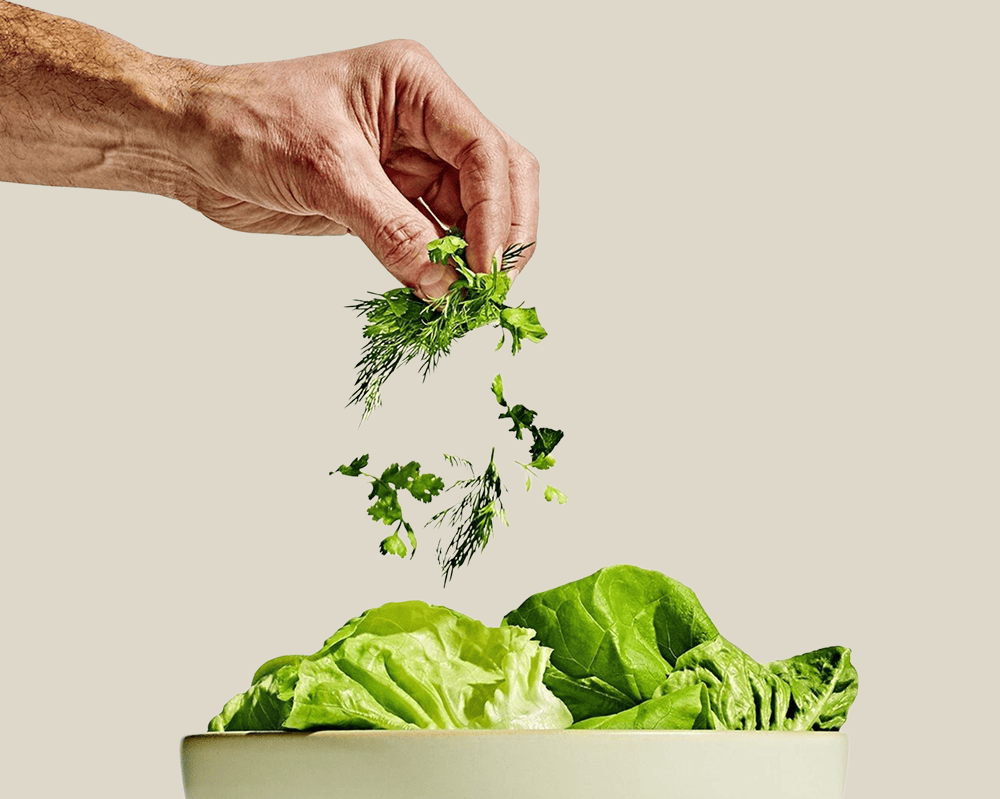 Fresh herbs being added to leafy vegetables