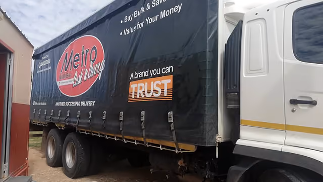 LKW mit schwarzem Planenaufbau und Werbung für Metro Cash & Carry mit Slogan 'A brand you can TRUST'.