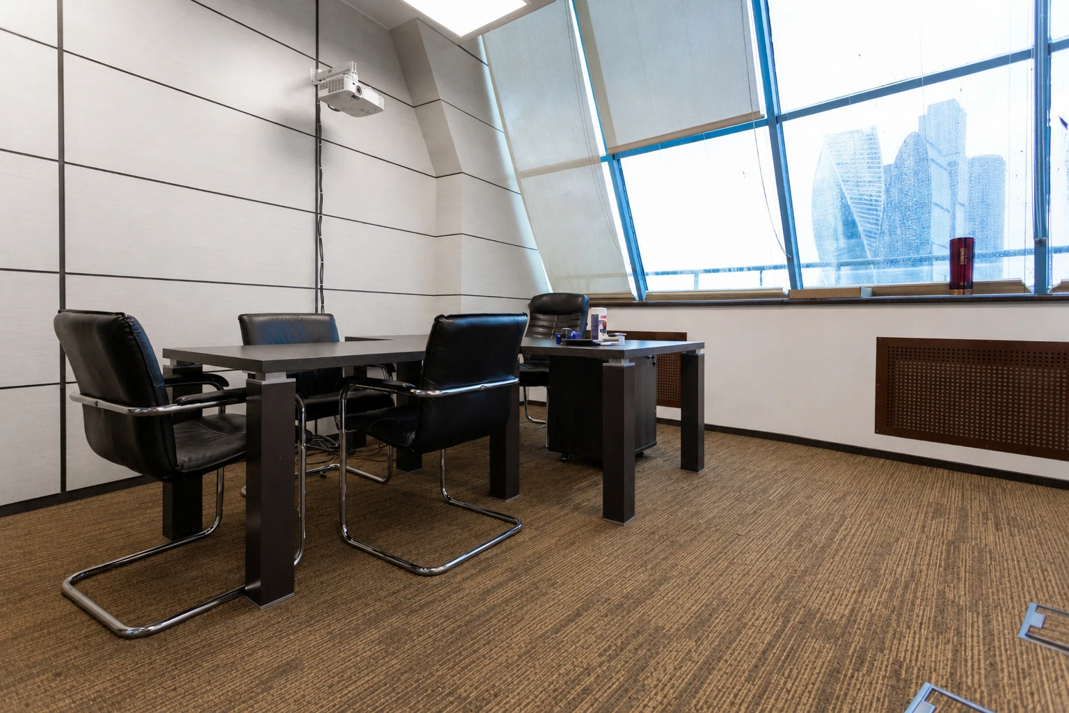 Wood-look carpet tiles in a small meeting room with a city view