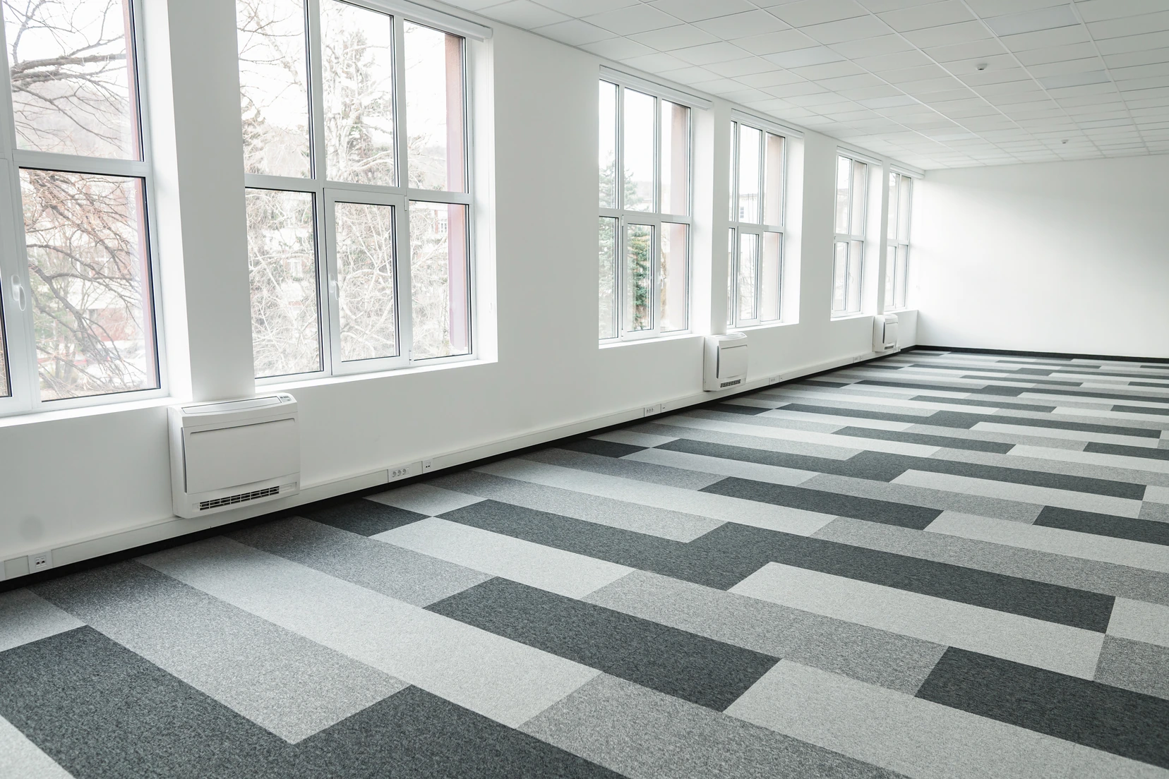 Grey and white carpet tile planks laid along a bright loft corridor