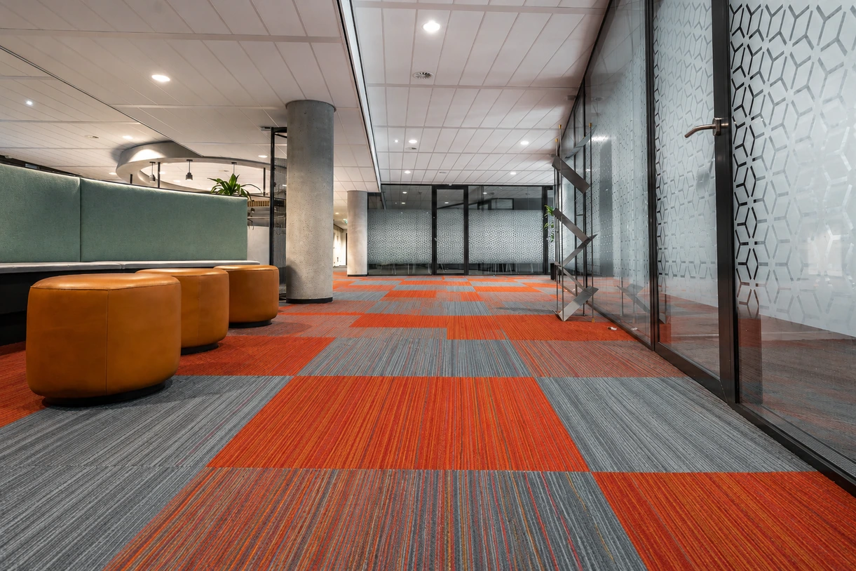 Orange, red and grey carpet tiles in an open office with lounge seating